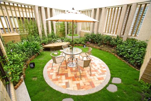 a patio with a table and chairs and an umbrella at Norway Forest Tamsui Motel in Tamsui