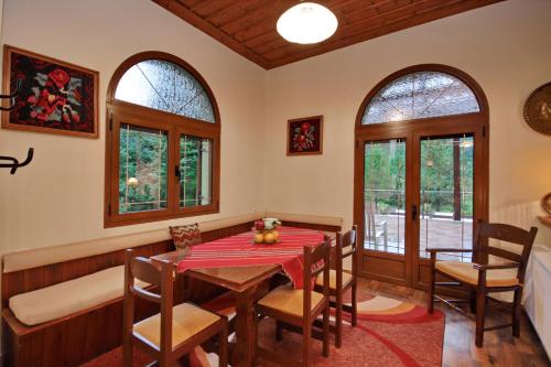 a dining room with a table and chairs and windows at Valtessiniko Studios in Valtessiniko