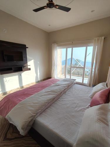 a bedroom with a large bed with a large window at Dual Lake in Bhīm Tāl