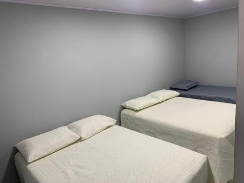 three beds in a room with white walls at Casa com Spa aquecido em Itajuba in Barra Velha