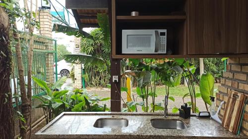 a kitchen with a sink with a microwave above it at Hotel Natur Campeche in Florianópolis