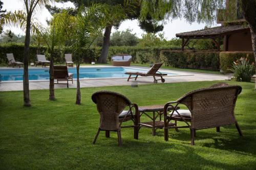 a group of chairs sitting in the grass near a pool at B&B Villa Seta in Agrigento