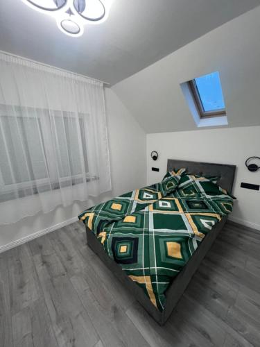 a bedroom with a bed with a green comforter at Casa Eva in Beclean