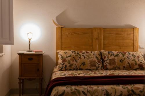 a bed with a wooden headboard and a lamp on a night stand at La Ferrara Agriturismo in Vairano Patenora