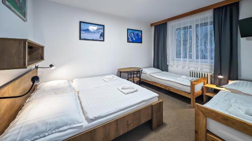 a bedroom with two beds and a window at Penzion Vápenka in Horní Maršov