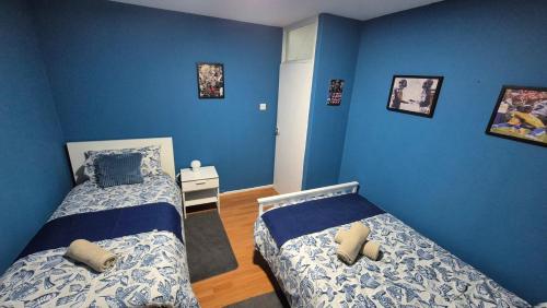 two beds in a bedroom with blue walls at Totteham stadium in London