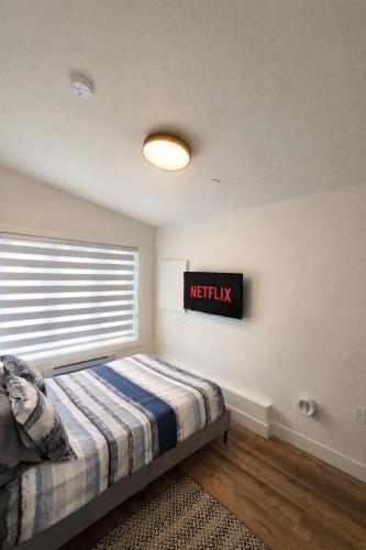 a bedroom with a bed with a netflix sign on the wall at 2BR Detached Guesthouse - Free Parking -10 mins to YVR & Downtown in Vancouver