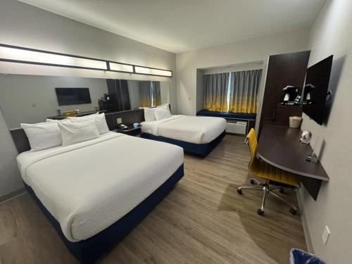 a hotel room with two beds and a desk at Microtel Inn & Suites by Wyndham Wheeling at The Highlands in Triadelphia