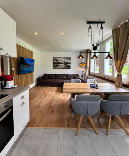 a kitchen and living room with a wooden table and chairs at Mountain View Apartment in Kandersteg