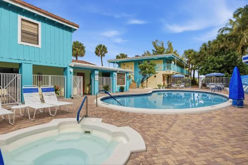 a swimming pool with chairs and a house at Sand Dune Shores in Palm Beach Shores