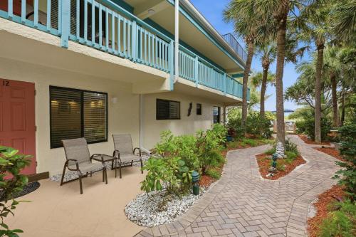 a patio with two chairs and palm trees at Sand Dune Shores in Palm Beach Shores