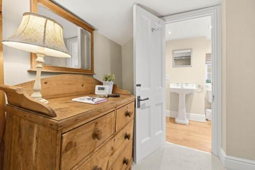 a lamp on top of a wooden dresser in a bathroom at WhiskAwayHomes - Hester'sHouse - Luxury Cottage in Broadway