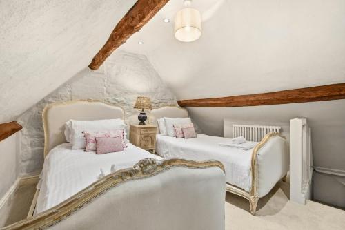 two beds in a attic room with white walls at WhiskAwayHomes - Hester'sHouse - Luxury Cottage in Broadway