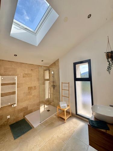 a bathroom with a shower and a sink and a skylight at Gîte du Colombier in Crestet
