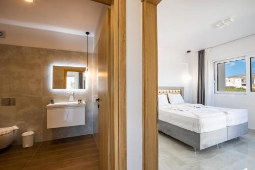 een slaapkamer met een bed en een badkamer met een wastafel bij Punta Mare Hotel in Karpathos