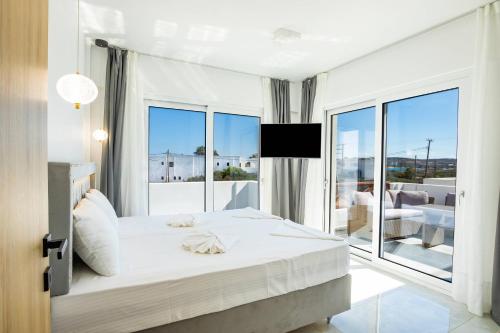 een witte slaapkamer met een groot bed en een balkon bij Punta Mare Hotel in Karpathos