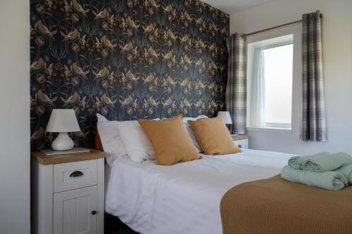 a bedroom with a white bed with a blue patterned wall at Stanton Lodge Cottage - 2 bedrooms - sleeps 5 in Curbar