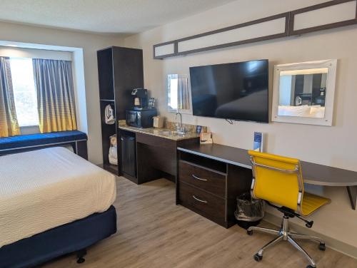 a hotel room with a bed and a desk with a television at Microtel Inn & Suites by Wyndham Wheeling at The Highlands in Triadelphia