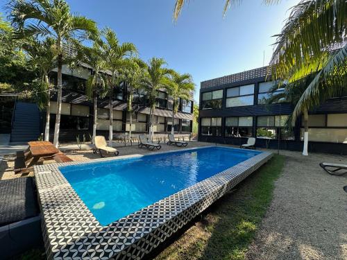 a swimming pool in front of a building with palm trees at Bacalar 102 Hotel in Bacalar