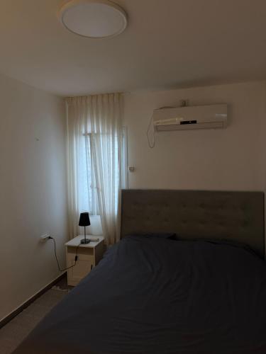 a bedroom with a bed and a fan and a window at The Urban Suite in Petaẖ Tiqwa