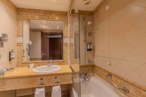 a bathroom with a sink and a tub and a mirror at Pestana Royal All Inclusive Ocean & Spa Resort in Funchal