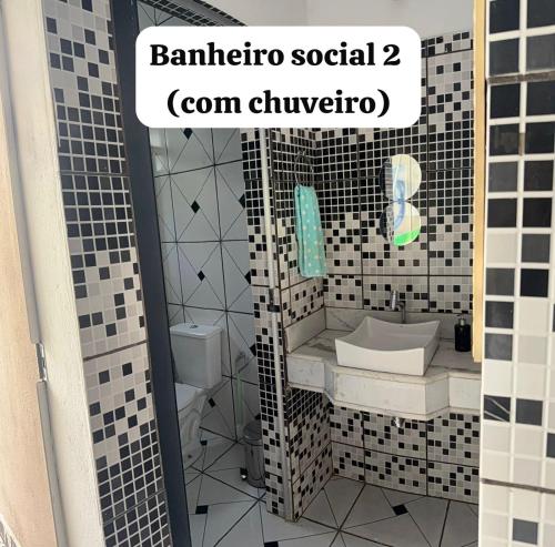 a bathroom with a black and white tiled wall at Pousada Coxim in Coxim