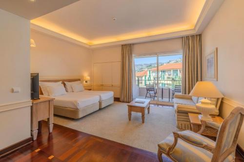 a hotel room with a bed and a desk and a television at Pestana Royal All Inclusive Ocean & Spa Resort in Funchal