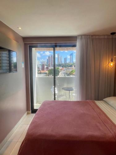 a bedroom with a large window with a view of the city at Manaíra Apart Hotel - Flat 201 in João Pessoa
