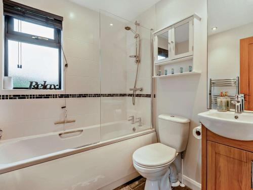 a bathroom with a toilet and a tub and a sink at 3 Bed in Swanage oc-94067 in Swanage