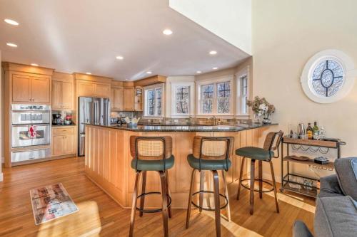 a kitchen with wooden cabinets and a bar with stools at Town & Tide Home for 8 in Kennebunkport