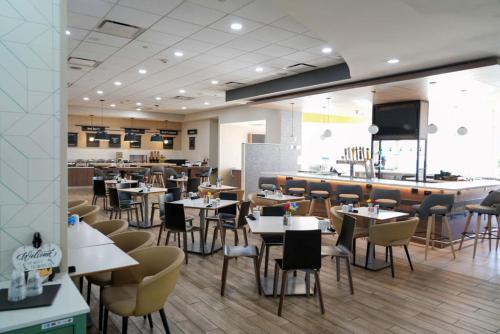 a restaurant with tables and chairs and a bar at Holiday Inn & Suites Phoenix Airport by IHG in Phoenix