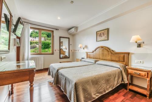 a bedroom with a bed and a desk and a window at Hotel Leku Eder in San Sebastián