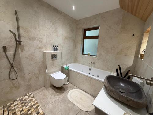 a bathroom with a tub and a sink and a toilet at Sessaigh lake studio in Dunfanaghy