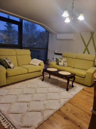 a living room with yellow couches and a coffee table at Apartament Kleopatra in Limanowa