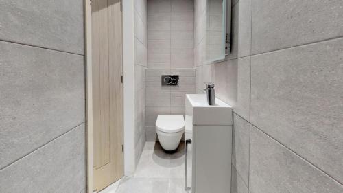 a white bathroom with a toilet and a sink at 3 Bed in Llanbedrog oc-llynor in Llanbedrog