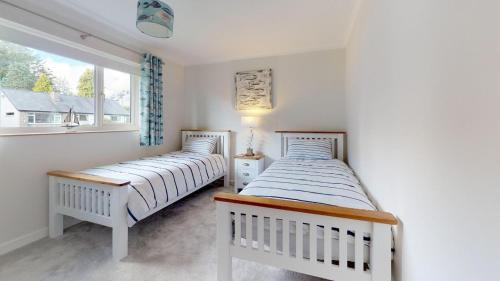 two beds in a room with a window at 3 Bed in Llanbedrog oc-llynor in Llanbedrog