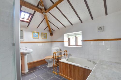 a bathroom with a tub and a toilet and a sink at 2 Bed in Caernarfon oc-wag263 in Llandegfan