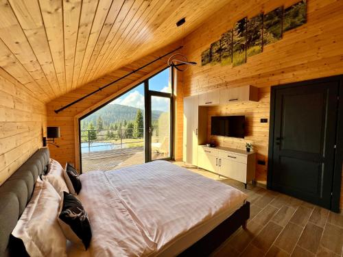 a bedroom with a large bed and a large window at Carpathic Chalet in Comandău
