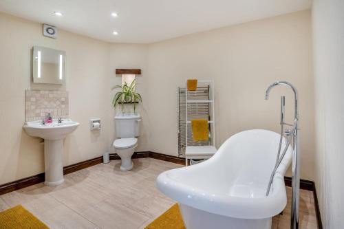 a bathroom with a tub and a sink and a toilet at 2 Bed in Trallong oc-bow106 in Sennybridge