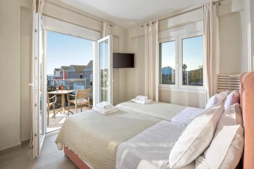 a bedroom with a large bed and a balcony at Thalia by Vintage Travel in Agios Georgios
