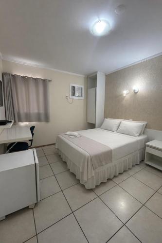 a bedroom with a bed and a desk in it at Copaiba Palace Hotel in Bauru