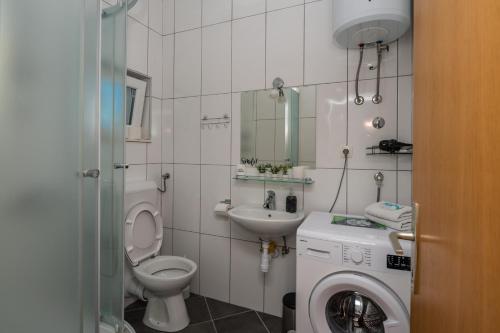 a bathroom with a toilet a sink and a washing machine at Holiday house Marijana in Zagvozd