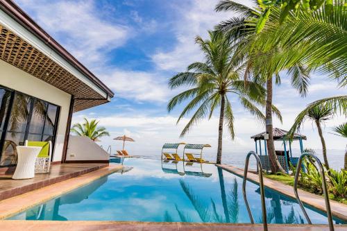 a swimming pool next to a house with palm trees at Mamburise Resort in Batan