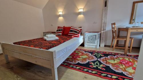 a bedroom with a bed with red pillows and a rug at Vila Studio Rasnov cu ciubar si sauna in Râşnov