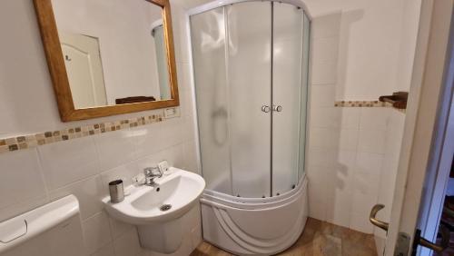 a white bathroom with a shower and a sink at Vila Studio Rasnov cu ciubar si sauna in Râşnov