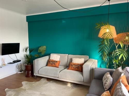 a living room with a couch and a green wall at Toi et Moi Apartments-Guests speek for us! in Ponta Delgada