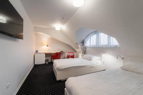 a bedroom with two beds and a desk and a window at EA Hotel Tereziánský dvůr in Hradec Králové