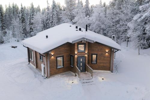 a log cabin in the snow with snow covered trees at Villa Vaellus in Ruka