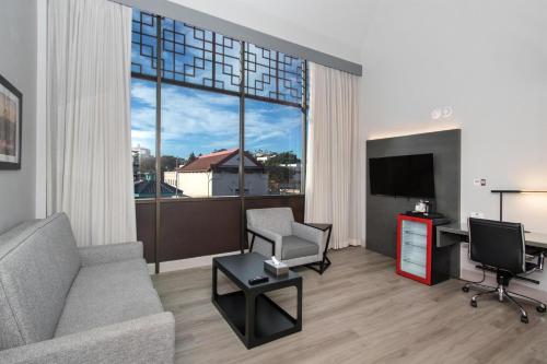 a living room with a couch and a desk and a large window at Aiden Los Angeles Downtown Dragon Gate Inn in Los Angeles
