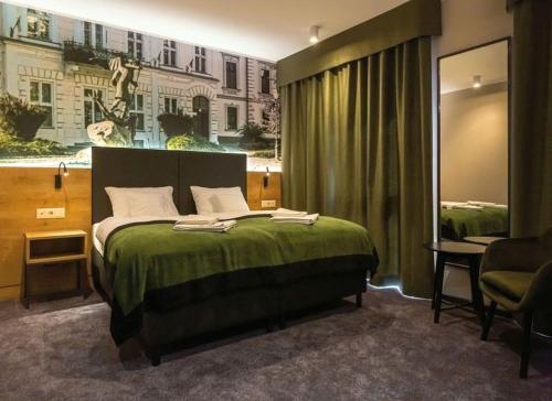 ein Schlafzimmer mit einem Bett mit einer grünen Tagesdecke in der Unterkunft Oliva Hotel in Veszprém